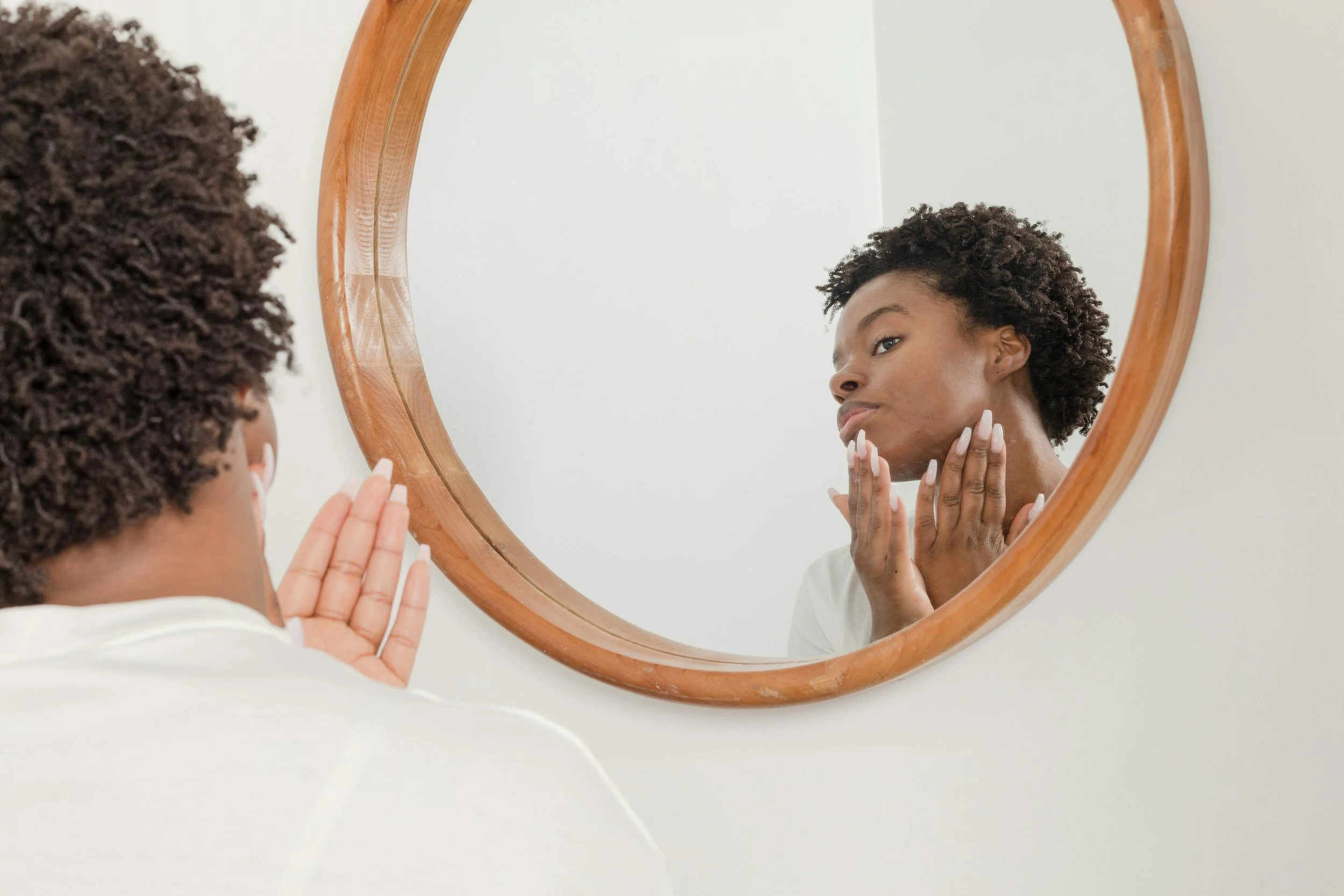 Person examining skincare in round mirror for beauty routine